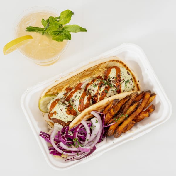 Mediterranean-style pita platter with creamy sauce, fries, cabbage salad, and a mint-garnished lemon drink.