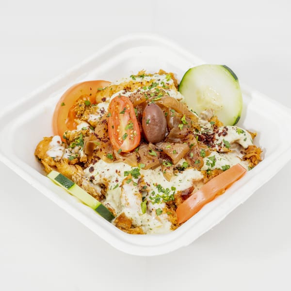 Loaded Mediterranean-style platter with crispy chicken, creamy sauce, roasted onions, olives, tomatoes, cucumber, and fresh herbs.